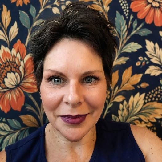 Lyd with short dark hair and berry lipstick against a colorful background